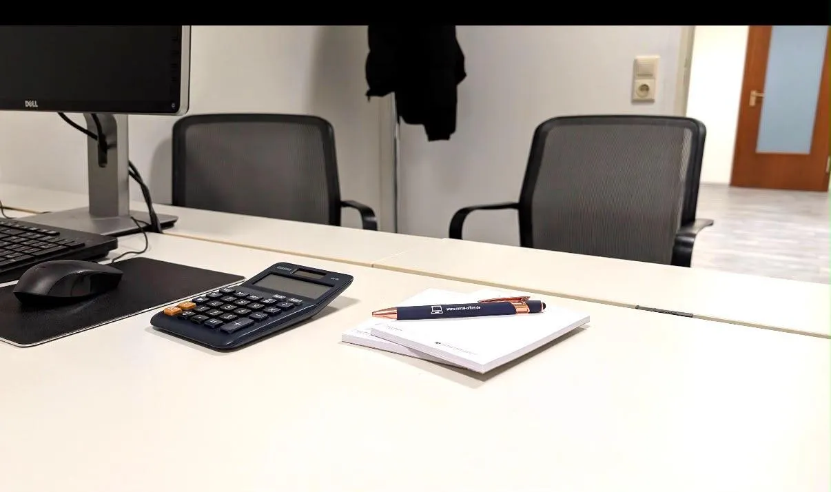 Arbeitsplatz mit Monitor, Taschenrechner und Schreibmaterial